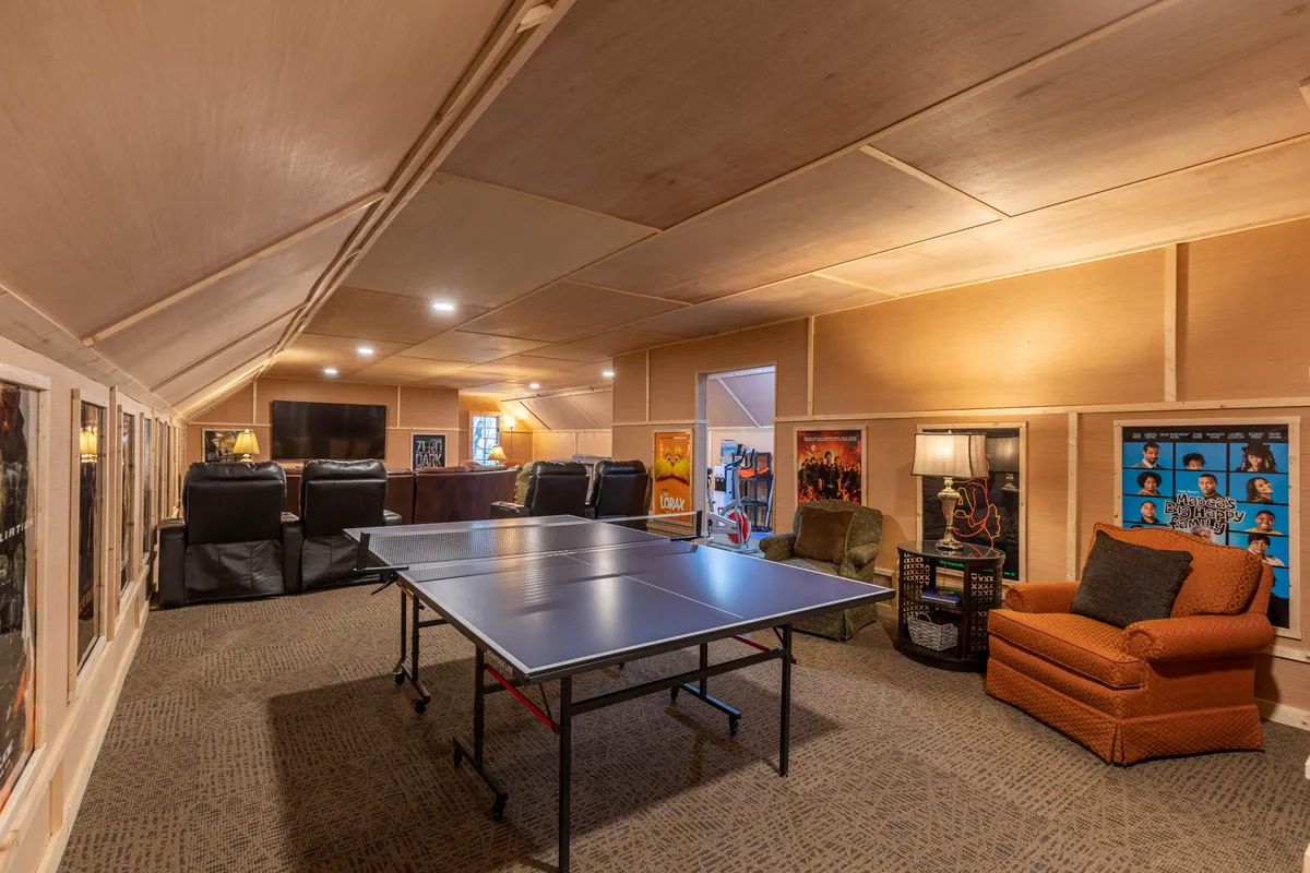 A playful game room scene centered on a ping pong table, with a nearby seating area and walls adorned with vibrant movie posters. The space exudes energy and friendliness, inviting guests to play, socialize, and immerse themselves in cinematic nostalgia.